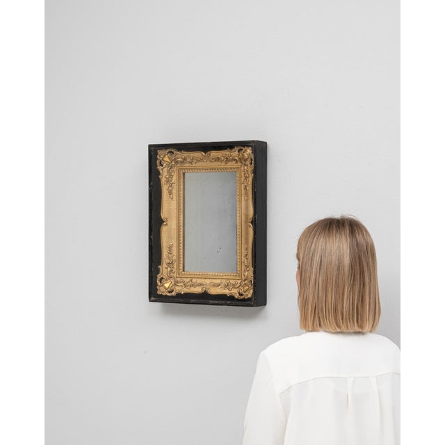 This 1980s French mirror pairs a gilded frame with a sleek black wooden display case. Scrolling foliage and floral relief...