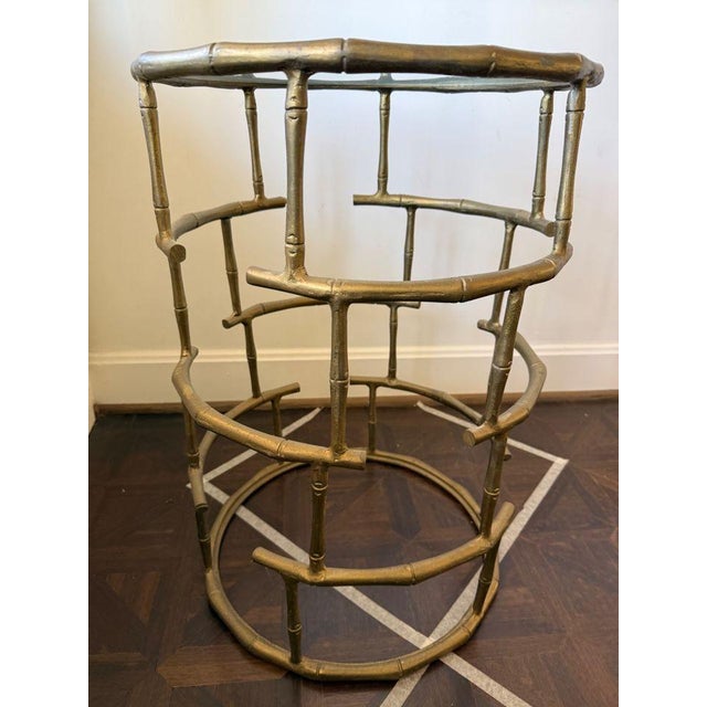 Chinoiserie meets Hollywood Regency in this gilt faux bamboo accent table. Features a circular glass top and an open,...