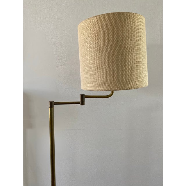 A handsome vintage brass floor lamp in classic library style, featuring a slender stem, an articulating swing arm for...