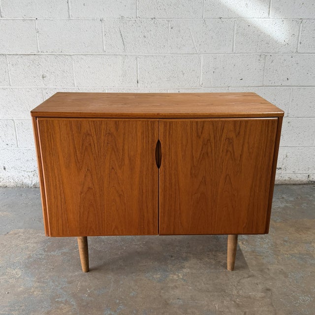 A vintage Danish teak sideboard with a compact apartment-friendly scale and clean cabinet front. The piece has two doors...