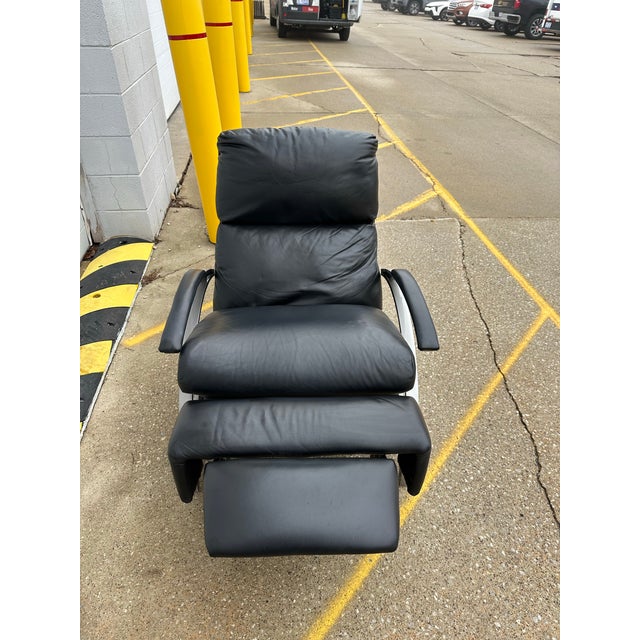 Clean Comfort Designs Inc. black leather and brushed chrome recliner. . Eye catching metal arms frame the piece; topped...