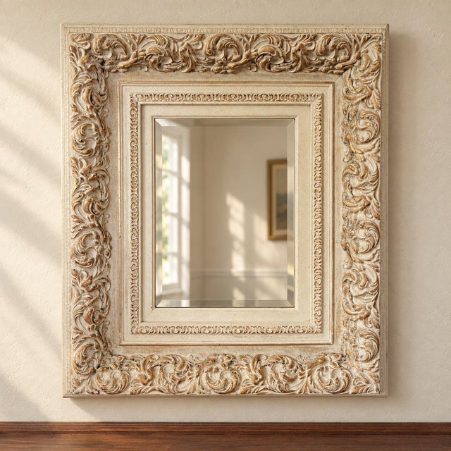A Mexican-made rectangular wall mirror with a broad cream-painted wooden frame and worn gold-toned accents. Raised...