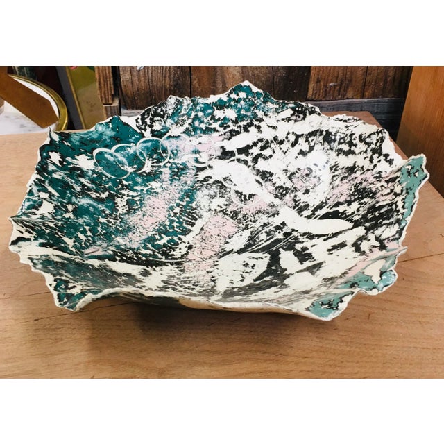 Vintage handmade white dish or plate with a splattered design in teal, pale pink and black with a jagged edge. This color...