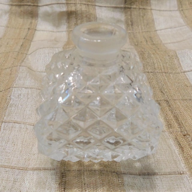 This is a small square diamond cut perfume bottle with a matching stopper. Both pieces are about the same shape and done...