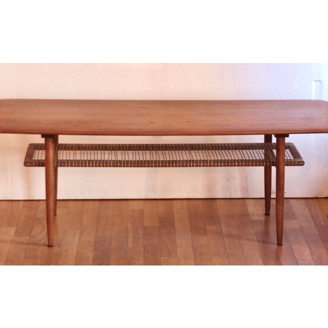 Teak wood side or coffee table in excellent condition. The top is made of teak wood, and the lower shelf is made of woven...