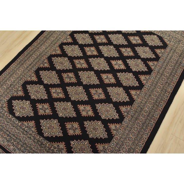 A tribal Bokhara rug hand-knotted with fine wool on a cotton foundation. This rug features rows of repeating medallions...