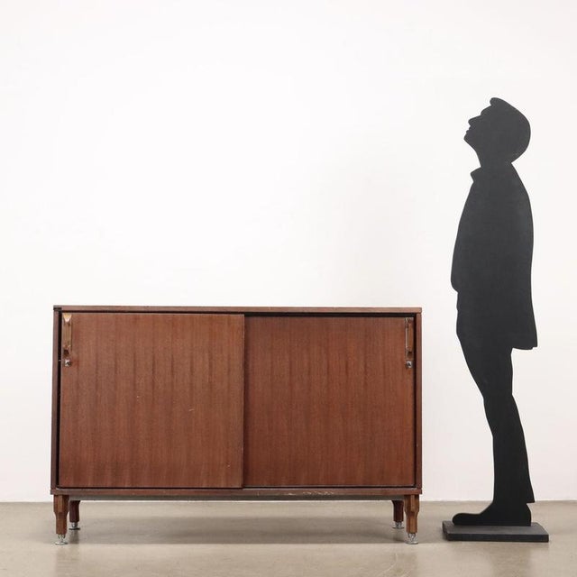 Sliding door cabinet, in teak veneer and formica. This piece is attributed to the mentioned designer/maker. It has no...