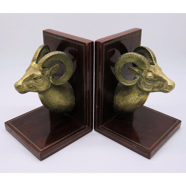 A pair of vintage brass ram's head bookends on lacquered wood bases with brass trim inlay. Unmarked, dated to mid-20th...