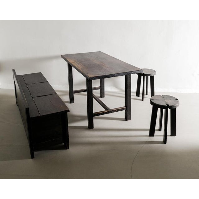 A rare french mid century wooden dining set consisting of a sofa, table and pair of stools in dark stained oak by an...