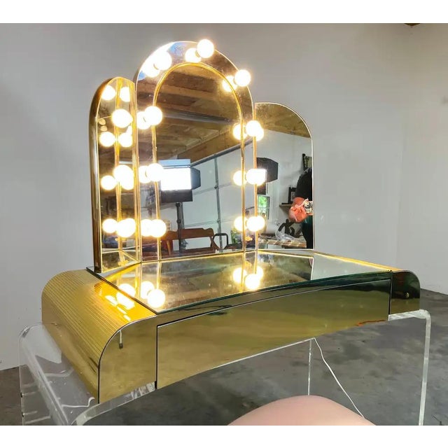 Elegant lucite single drawer vanity with light up arched mirror having brass toned accents along the corners and front...