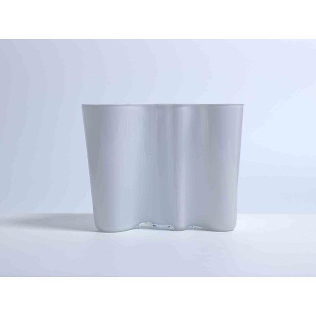 Vintage white jacketed glass vase designed by Alvar Aalto and realized by Iittala, Finland. Realized since 1960s, this...