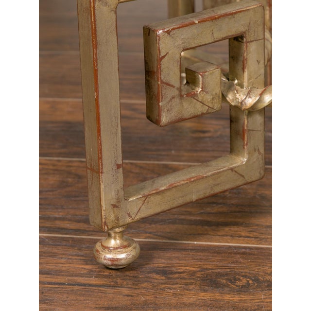 A French vintage silver leaf iron center table from the mid-20th century, with circular glass top and Greek Key motifs....