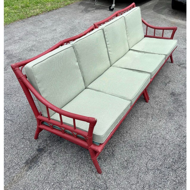 A fabulous vintage 2-piece bamboo and rattan sectional sofa with older red paint, showing nice age and patina. Includes...