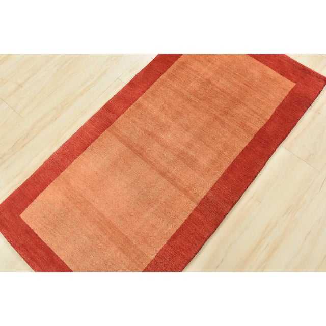 A contemporary Gabbeh rug hand-knotted with an all-wool pile on a cotton foundation. This finely woven area rug features a...