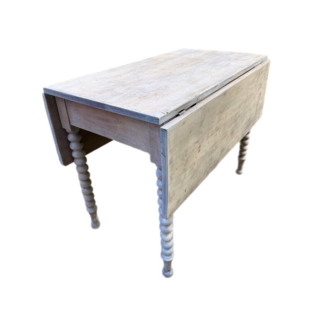 19th century Swedish farmhouse style drop leaf table with bobbin turned legs. It has been stained a pickled white, which...
