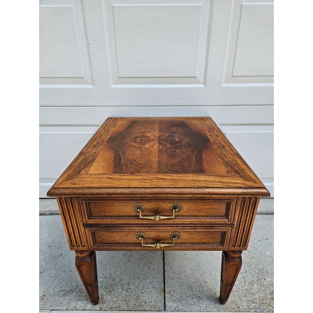 A classic Henredon side table with two drawers and a banded top surrounding book matched walnut veneers. This table has...