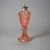 An antique oil lamp offers pink pressed glass construction with paneled coinspot pattern raised on column with hexagonal...