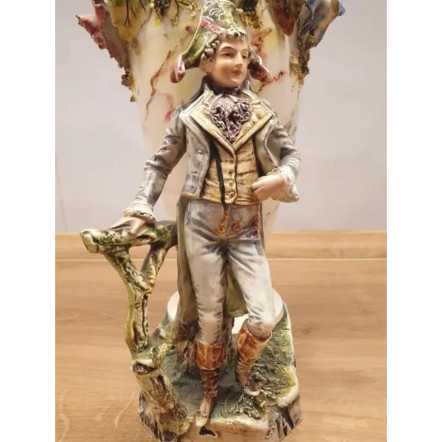 Large and richly decorated porcelain vase featuring a sculpted standing figure in Napoleonic attire forming the base. The...