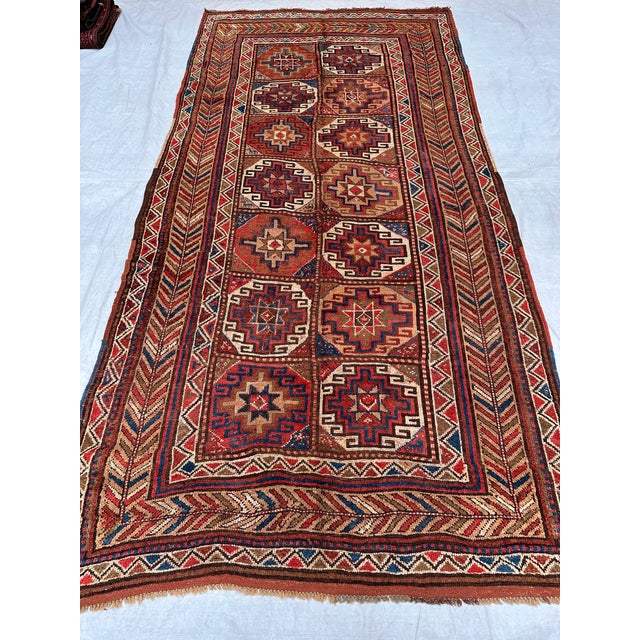 This antique hand-knotted Khamseh Qashqai rug features two columns of compartmentalized star medallions in rust, ivory,...