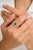 This modern designer ring showcases a stunning natural oval-cut emerald, flanked by brilliant diamonds that enhance its...