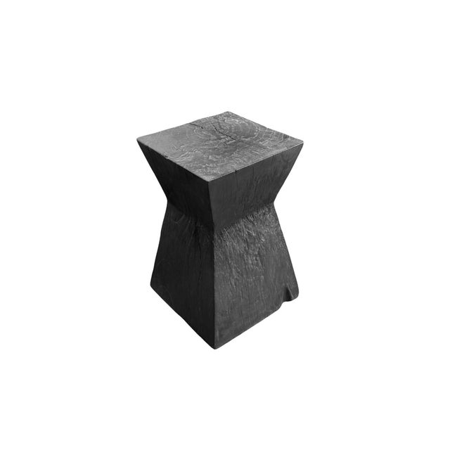 Hand-carved from a single block of solid suar wood, this sculptural side table is a striking expression of natural...