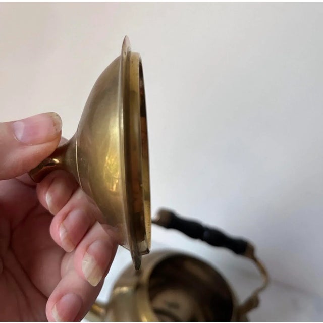 This is a vintage or antique brass teapot, also referred to as a brass kettle. The teapot has a polished brass finish and...