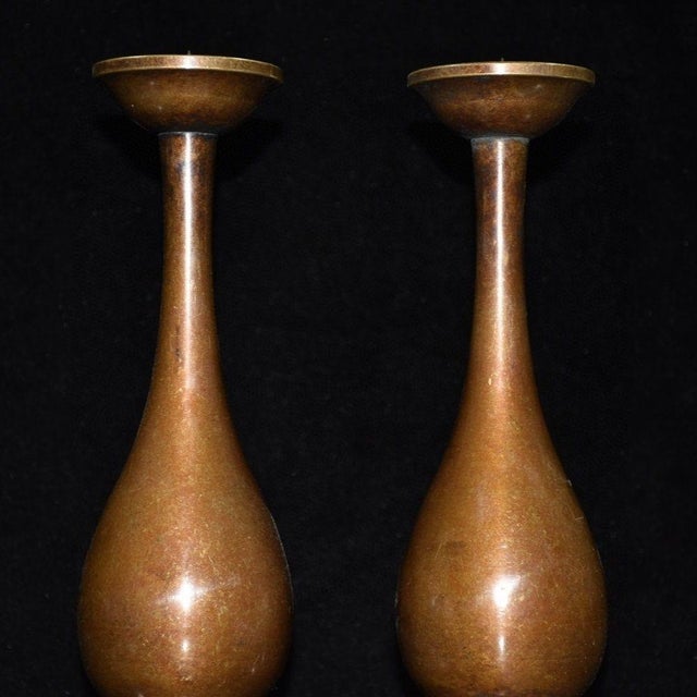 Graceful matched pair of solid copper tall candlesticks. Features a slender elongated neck rising from a smooth pear-...