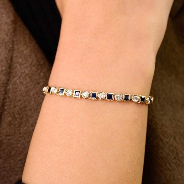 This elegant tennis necklace features 25 Princess Cut Natural Blue Sapphire totaling 3.7 carats, set in 14k yellow gold....