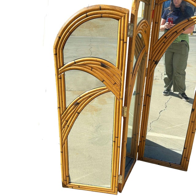 This beautifully restored Art Deco rattan folding screen mirror featuring two hinged panels with arched tops and curved...