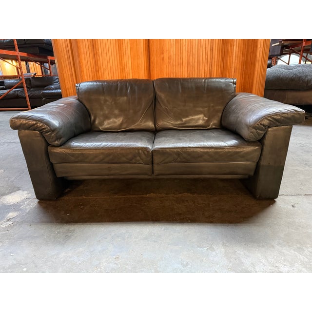 Two-seater Italian sofa in brown leather and down-filled cushions. Good vintage condition with some patina. This piece has...