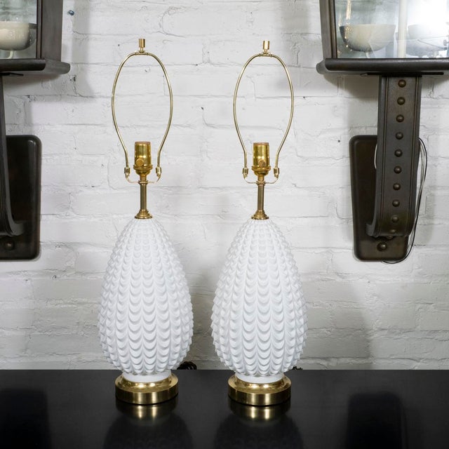 Pair of white molded glass table lamps with brass hardware.