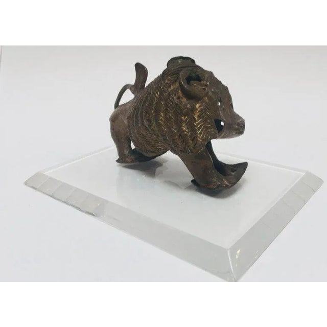 A highly expressive vintage African cast-bronze sculpture depicting a stylized mythical lion, attributed broadly to a West...