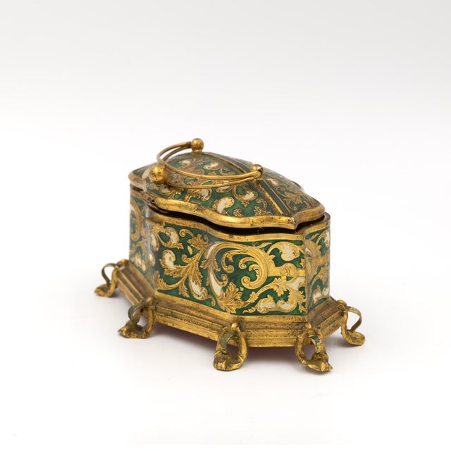 Of octagonal serpentine form, the body and domed lid in green enamel over gilt metal, decorated on all sides with...