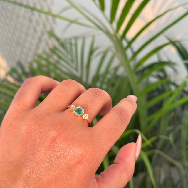 This Trilogy ring features a 0.46 carat round cut natural emerald set in 14k yellow gold. The center stone measures...