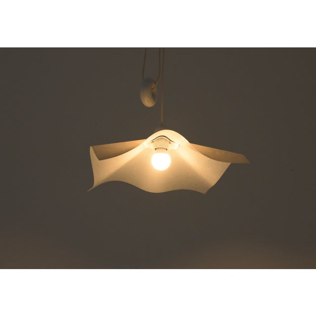 Mario Bellini's paper and plastic pendant light with a donut-shaped counterweight, model: Area 50. Easily height-...