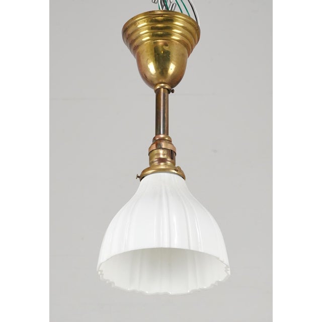 Early 20th century Traditional style pendant light with a fluted milk glass shade and a short brass pole fitter. This...