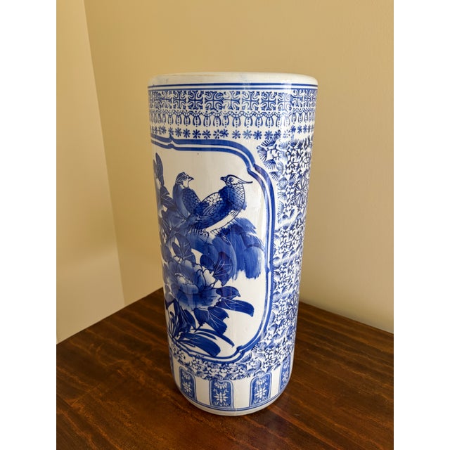 A classic blue and white porcelain umbrella stand in the chinoiserie tradition, featuring finely rendered birds among...