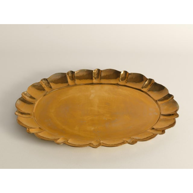 Masterfully crafted brass tray featuring an oval shape with a gracefully contoured, hand-hammered edge. Manual operation...