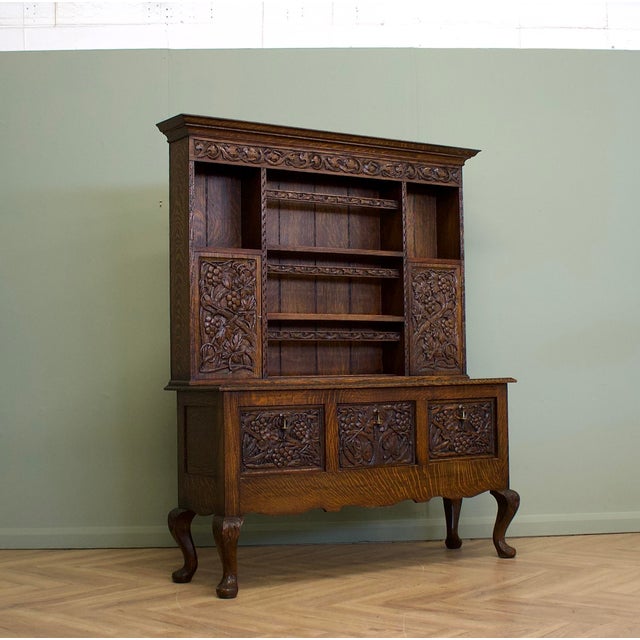 A substantial carved oak dresser dating from the late 20th century, designed in a Jacobean Revival style. The upper...