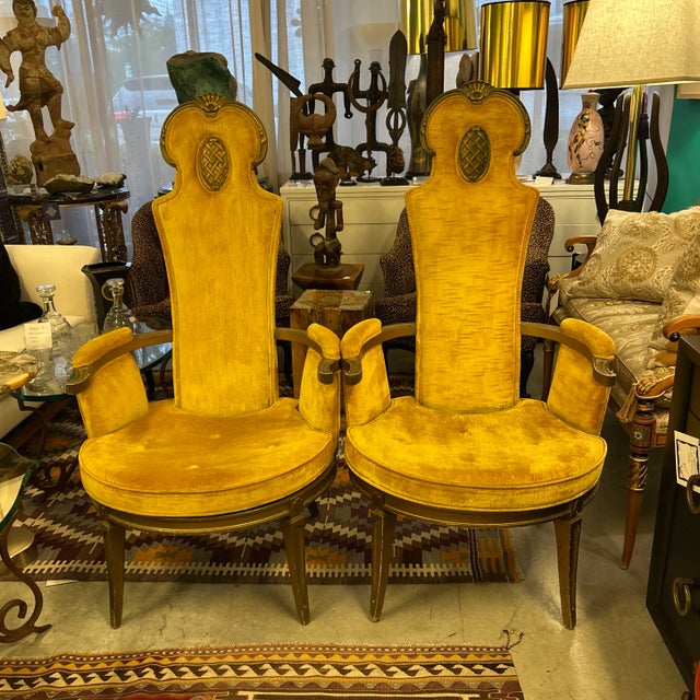 Pair of mid century tufted gold velvet arm chairs with wood frames. They have carved shell designs at the top and carved...
