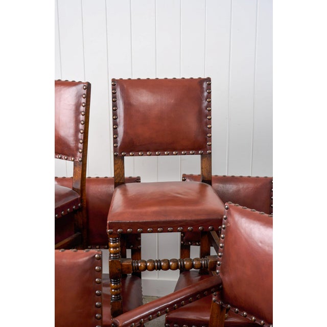 This set of ten English Cromwellian-style dining chairs features bobbin-turned front legs and front stretchers and leather...