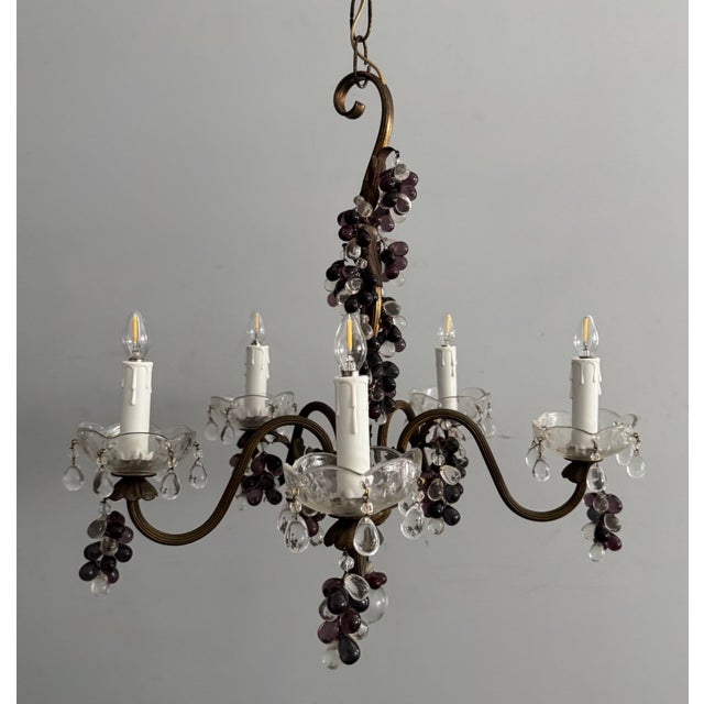 Beautiful, antique chandelier consisting of a a scrolled brass frame adorned with glass grape clusters ranging in tones...