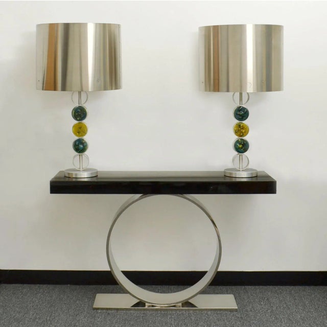 The raak table lamps are large, modern and of a simple design executed in aluminium, stainless steel and melted glass,...