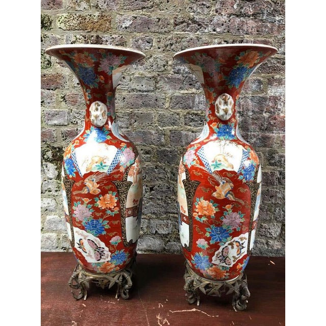 A monumental pair of japanese meiji period imari porcelain vases, with foliage bronze stands, dating from the late 19th...