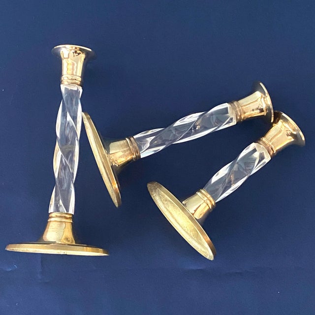 Set of 3 Hollywood Regency style solid brass and twisted lucite candleholders. They measure 7.25”, 6.25” and 5.25” tall...