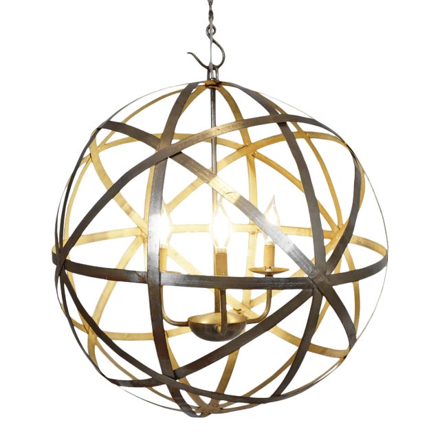 Crafted from iron with a warm brass finish, this striking globe-shaped chandelier features intersecting metal bands...