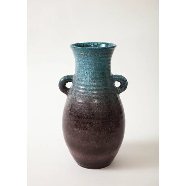 A ceramic jug with two handlesin a beautiful glaze of blue and aubergine produced by Accolay Pottery. Founded in the 1950s...