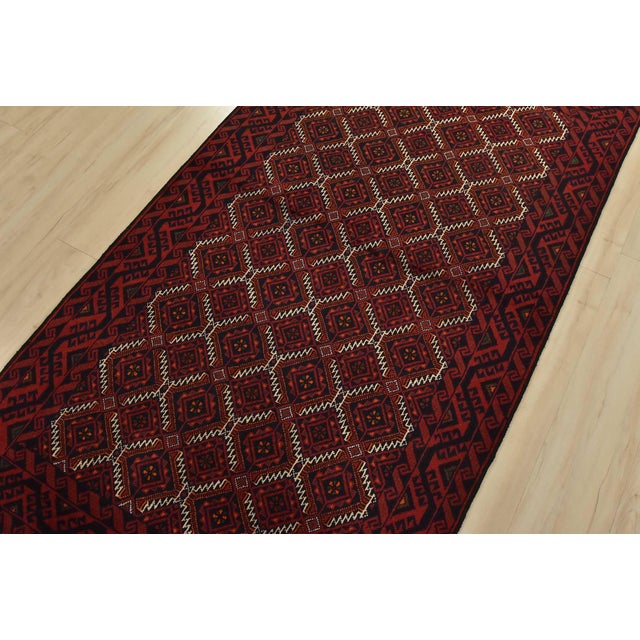 An authentic vintage tribal Baloch rug hand-knotted with fine wool and natural dyes. This nomadic carpet features an all-...