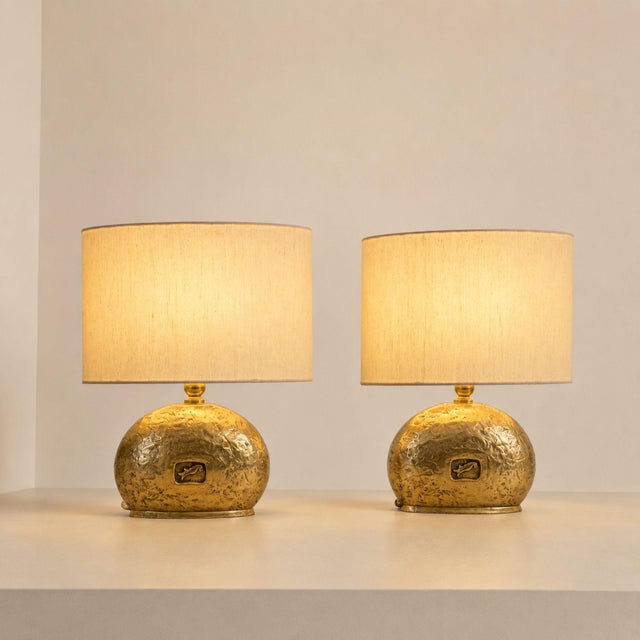 Elegant pair of Italian table lamps from the 1970s, crafted in cast brass and completed with oval fabric shades. Each lamp...