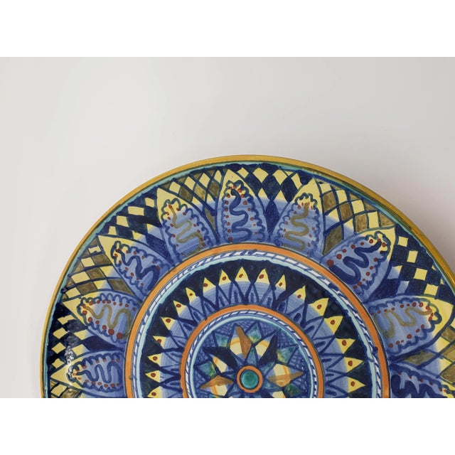 This hand-painted hanging plate features a blue and ochre geometric design perfect to accent a Mediterranean-inspired...